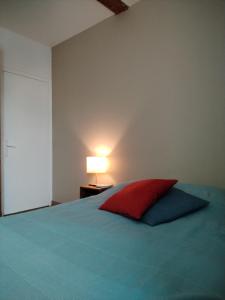 ein Schlafzimmer mit einem Bett mit einem roten Kissen und einer Lampe in der Unterkunft Le Clos du Marronnier in Cully