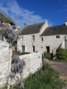 ein Haus mit einer Steinmauer und einem Baum mit lila Blumen in der Unterkunft Le Clos du Marronnier in Cully