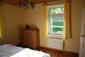 a bedroom with a bed and a window with yellow curtains at Häuschen in Utarp in Utarp