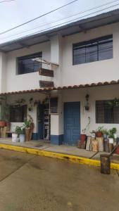 a white building with blue doors and windows at Hospedaje Quillabamba in Santa Teresa