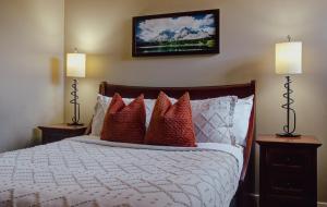 Panoramic Mountain View Condo في كانمور: غرفة نوم بسرير ومخدات حمراء ومصباحين