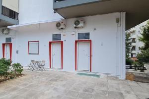 a white building with red doors and chairs on it at LoftLiving 2 by ΑΤΤΙΚΟ ΝΟΣΟΚΟΜΕΙΟ in Athens