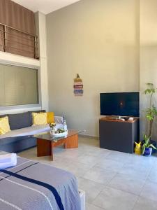 sala de estar con cama y TV de pantalla plana en Cozy apartment near to the airport en Kouvarás