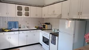 a kitchen with white cabinets and a white refrigerator at Green Haven Cottage in Delvinë
