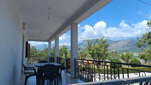 a balcony with a table and chairs and a view of mountains at Green Haven Cottage in Delvinë