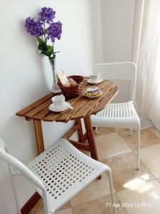 uma mesa de madeira com um vaso de flores e duas cadeiras em IL GIARDINO em La Spezia