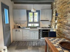 a kitchen with white cabinets and a brick wall at Nightsky Tinos Villa w Unrestricted View in Tripótamos