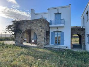a white house with a stone wall and a balcony at Nightsky Tinos Villa w Unrestricted View in Tripótamos