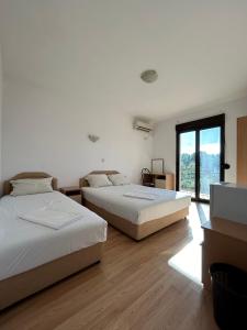 Duas camas num quarto branco com uma janela em GuestHouse Moco Forest em Ulcinj