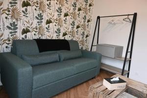 a living room with a green couch and a table at Le Botanique Centre Clim WIFI in Châteauroux +4 photos