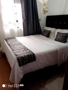 sypialnia z łóżkiem z białą pościelą i poduszkami w obiekcie faraja homes w mieście Kakamega
