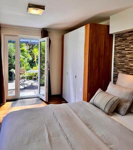 - une chambre avec un lit et une porte coulissante en verre dans l'établissement Garten Apartment am Fluss, à Eriskirch