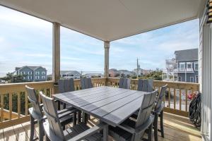 a wooden table on a deck with chairs at Azure home in Emerald Isle
