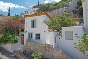 a white house with a gate and a wall at Douskos Citrus Apartments in Hydra