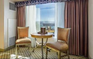 リノにあるReno Suites Hotelのテーブルと椅子2脚、窓が備わる客室です。