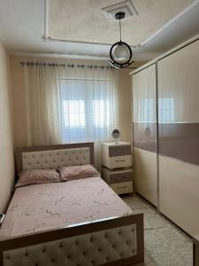 ein Schlafzimmer mit einem Bett, einer Kommode und einem Fenster in der Unterkunft Vila Mani in Durrës