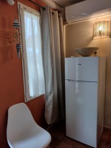 een witte koelkast in een kamer met een witte stoel bij Vacances en Camargue proche de la mer climatisé in Aigues-Mortes +13 foto's