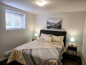 a bedroom with a large bed with two lamps at walkout suite in willoughby in Langley