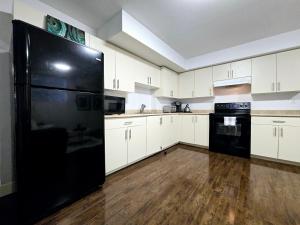 a kitchen with white cabinets and a black refrigerator at walkout suite in willoughby in Langley