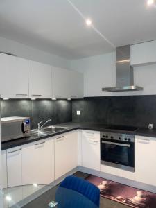 a kitchen with white cabinets and a blue chair at Elo Global Appart in Buttes