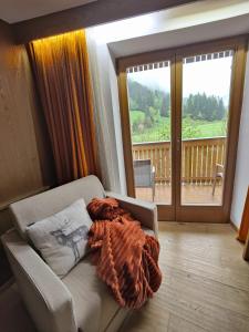 a living room with a chair and a large window at Hotel Alpenblick in Sarntal