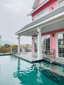 a swimming pool in front of a pink house at Lucia Villa - Melorita Hòa Lạc in Hanoi