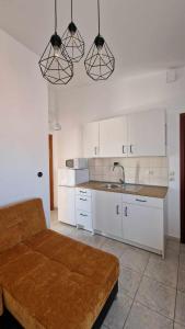 a kitchen with white cabinets and a sink and a couch at Kofinaki apartment 2 in Tycherón