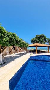 una piscina azul junto a un pabellón en A Poucos Passos da Praia Condomínio Arauá Ilha de Itaparica en Vera Cruz de Itaparica