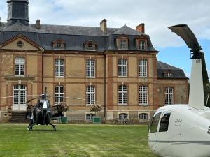 un helicóptero estacionado frente a un gran edificio en 24H LE MANS Château de Lauresse chambres d'hôtes Luxe en Le Mans