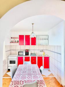 a kitchen with red cabinets and a table with chairs at Dalmatian House, spacious stone terraces, balcony , views in Dubrovnik