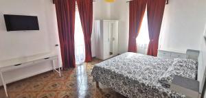 een slaapkamer met een bed, rode gordijnen en een tv bij Path of gods in Pianillo
