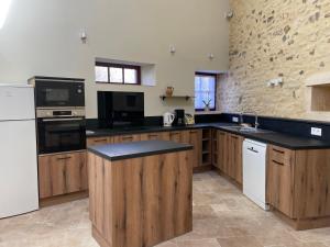 a kitchen with black counter tops and wooden cabinets at Gîte La Maison des Poètes de 1 à 6 personnes à Treigny Perreuse in Perreuse