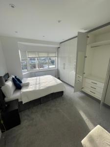 a white bedroom with a large bed and a window at Grey Home Near wembley arena in Wealdstone