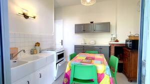- une cuisine avec une table et des chaises vertes dans l'établissement A l'Ombre du Jardin YourHostHelper, à Saint-Georges-de-Didonne