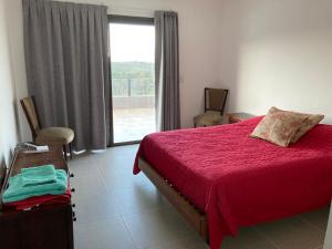 a bedroom with a red bed and a large window at Casal Sur in Potrero de Garay