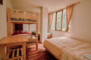 a bedroom with two bunk beds and a table and a desk at Backpackers-balcones-river-lodge in Baños