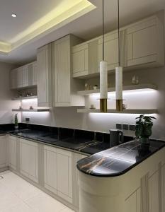 a kitchen with white cabinets and a black counter top at fin apartment C6 in Riyadh