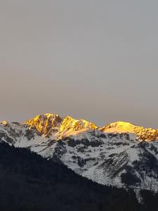 um grupo de montanhas cobertas de neve com o sol brilhando sobre eles em Gite de l'Ours em Saint-Mamet