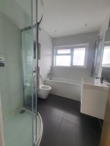 a bathroom with a tub and a sink and a toilet at Grey Home Near wembley arena in Wealdstone