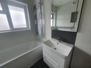 a white bathroom with a sink and a window at Grey Home Near wembley arena in Wealdstone