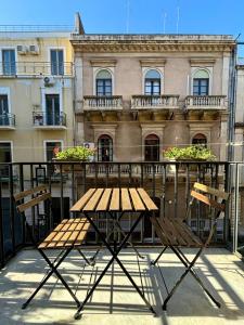 uma mesa de madeira e cadeiras em frente a um edifício em Casa MiRè em Catânia
