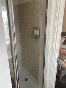 um chuveiro com uma porta de vidro ao lado de uma cama em Cheerful 4 Bedroom Townhouse with free parking em Kenton