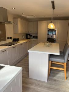 a kitchen with white cabinets and a island with a chair at The Old Coach House at BYRE HOUSE 