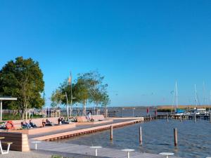 people sitting on a dock next to a body of water at Doppelzimmer mit Seeblick - Neusiedlersee in Breitenbrunn