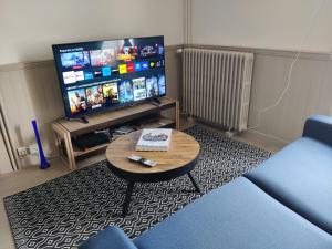 uma sala de estar com uma mesa e uma televisão de ecrã plano em Appartement BLUEMA 2 chambres RdC em Vitré