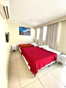 una camera con due letti e una coperta rossa di Cobertura com Piscina Andrei Noriller Vista Mar ad Arraial do Cabo