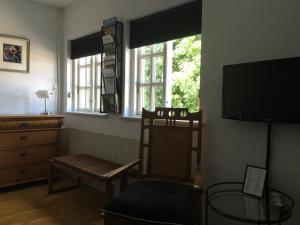 sala de estar con silla, TV y ventanas en Bed and Breakfast The Old Chestnut Tree Silkeborg en Silkeborg