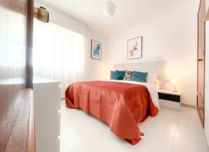 - une chambre blanche avec un lit et une couverture orange dans l'établissement Esmeralda Minerva Primera Línea Fossa- Levante Beach, à Calp