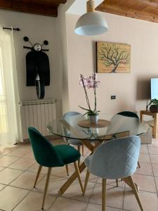 a dining room with a glass table and green chairs at Casa An'anasha in Luino