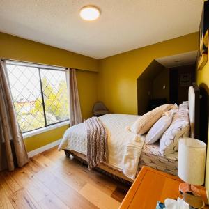 a bedroom with a bed and a large window at Oceanside Manor (Beach View) in Qualicum Beach